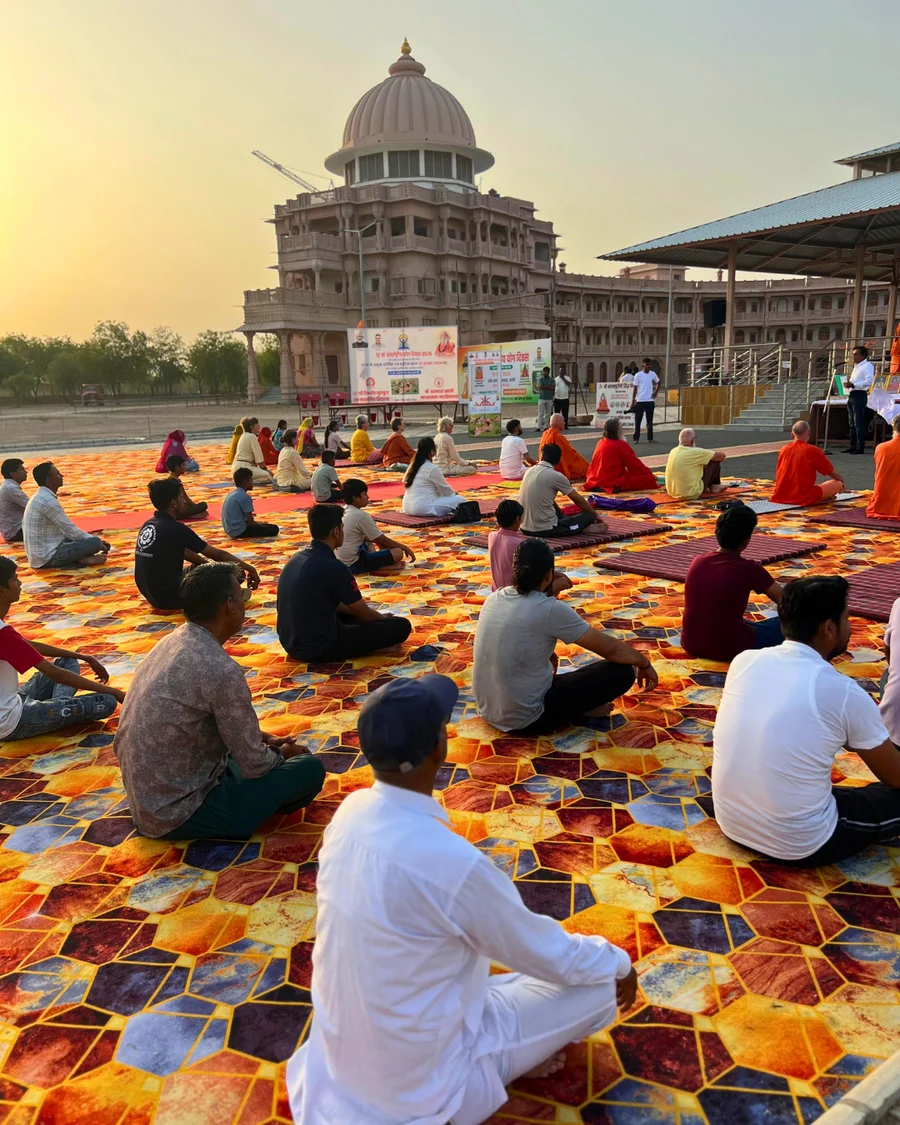 A large crowd of over 200 people practicing yoga in front of the grand Shiva Temple at OM Ashram.